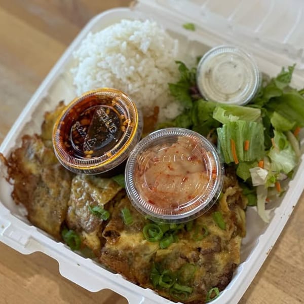 A Wailua Drive In Hawaiian plate lunch with meat, rice, salad, and three sauces in a to-go container.